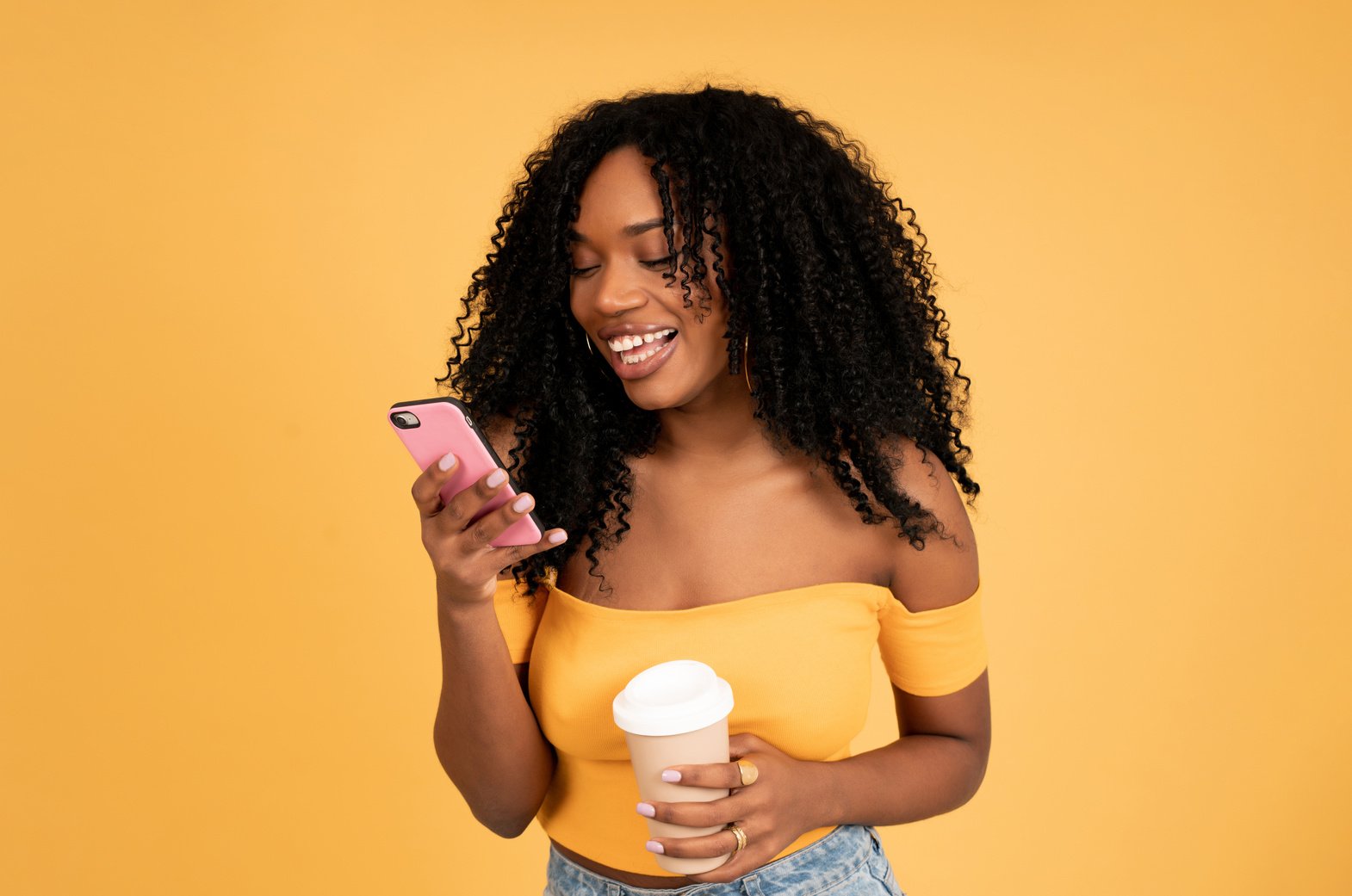 Afro Woman Smiling While Looking at a Mobile Phone.